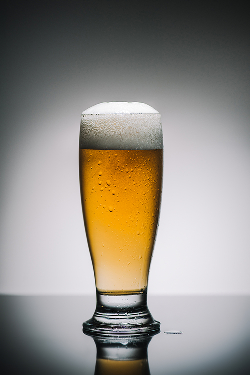 full glass of beer with foam on table