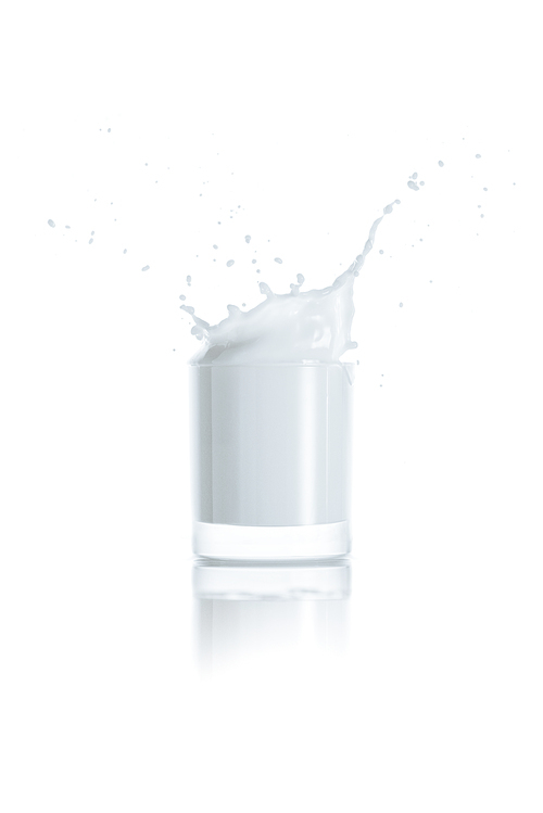 full glass of milk with splash, on white with reflection