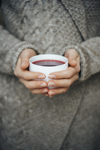 close-up partial view of girl holding cup of tea in hands