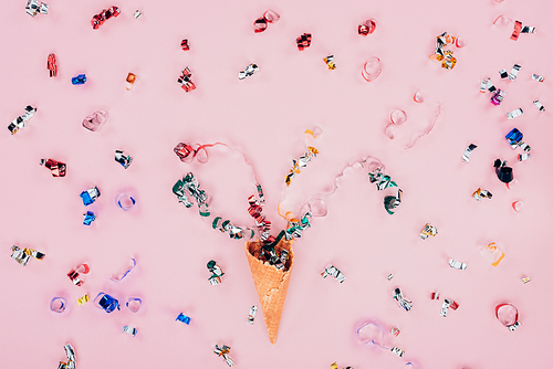 top view of confetti spilling out waffle cone, isolated on pink