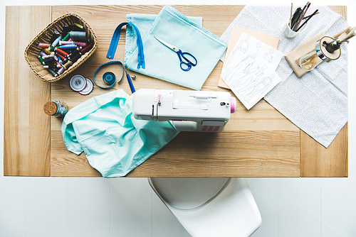 top view of seamstress workplace with fabric, sewing machine, drafts and stitchings