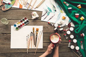 Cropped image of artist drinking coffee at working place