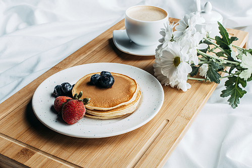 breakfast in bed with pancakes and coffee on wooden tray