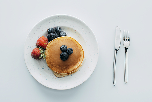 top view of pancakes with blueberries and strawberries on white table