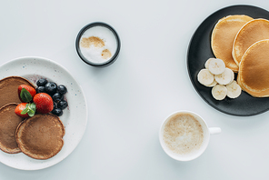 top view of delicious breakfast for two with pancakes and coffee on white table