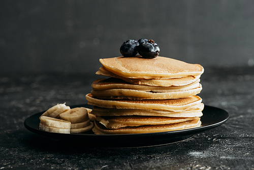 delicious stacked pancakes with blueberries and sliced banana