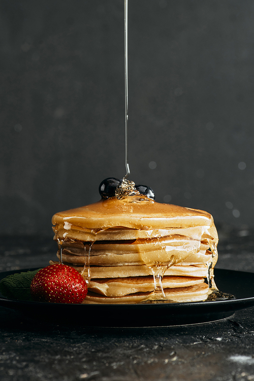 close-up shot of maple syrup pouring onto stacked pancakes