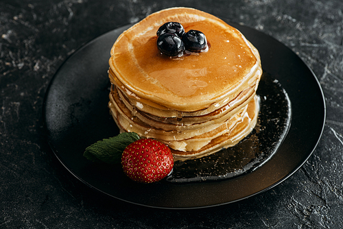 stack of freshly backed pancakes with berries on black table