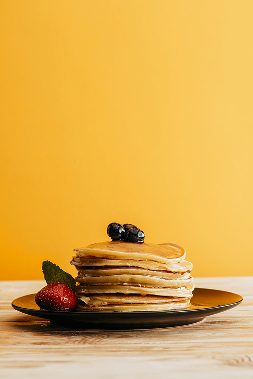stack of delicious pancakes with berries on yellow