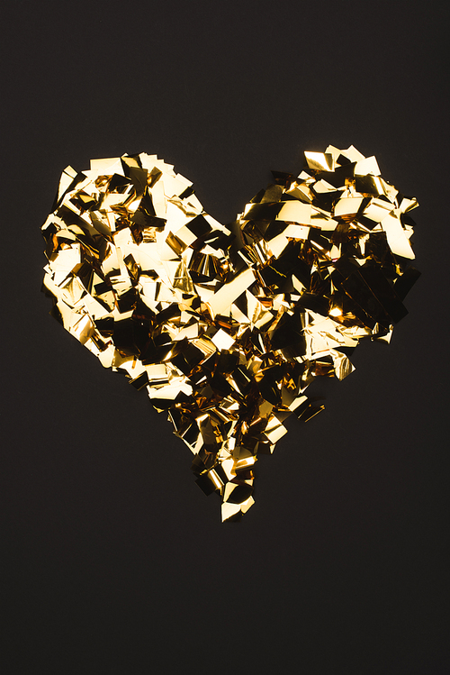 top view of golden confetti arranged in heart shape isolated on black