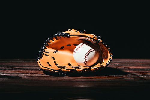close-up view of baseball ball and glove on wooden table