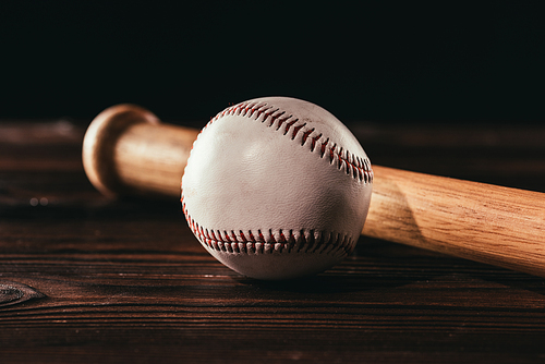 close-up view of white leather baseball ball and bat on wooden table