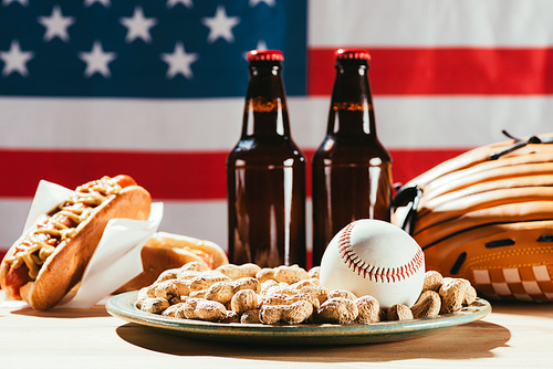 close-up view of baseball ball on plate with peanuts and beer bottles