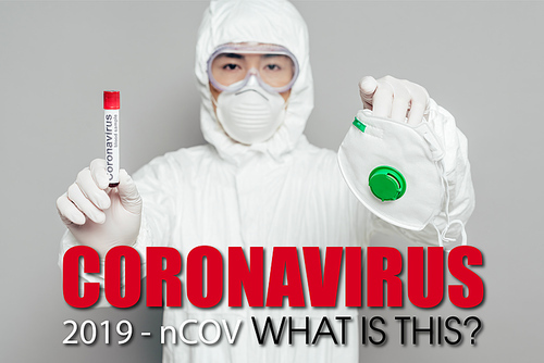 asian epidemiologist in hazmat suit  while holding respirator mask and test tube with blood sample on grey background, coronavirus illustration