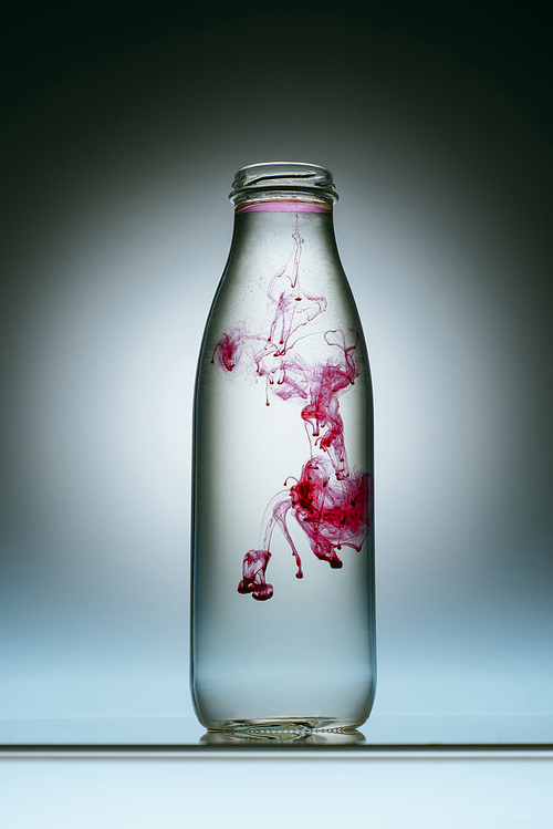 close up view of pink paint splash in bottle of water