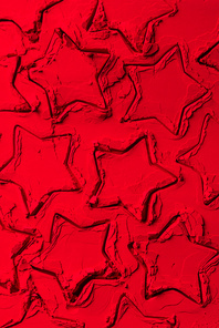 top view of shapes of cookie cutters in shape of stars on red powder