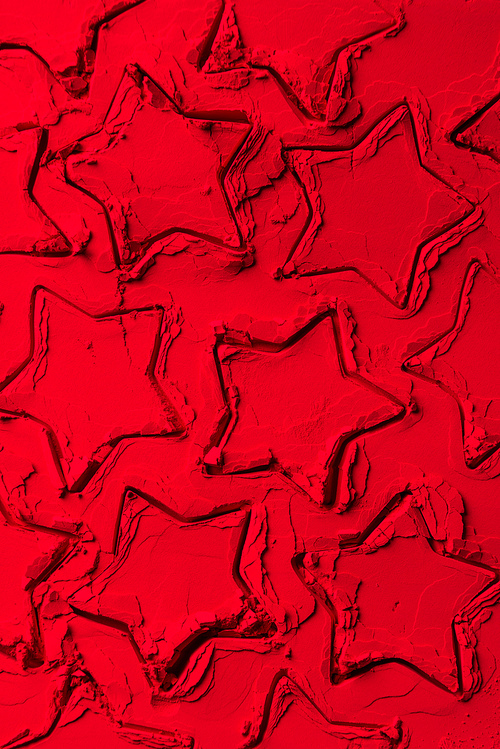 top view of shapes of cookie cutters in shape of stars on red powder