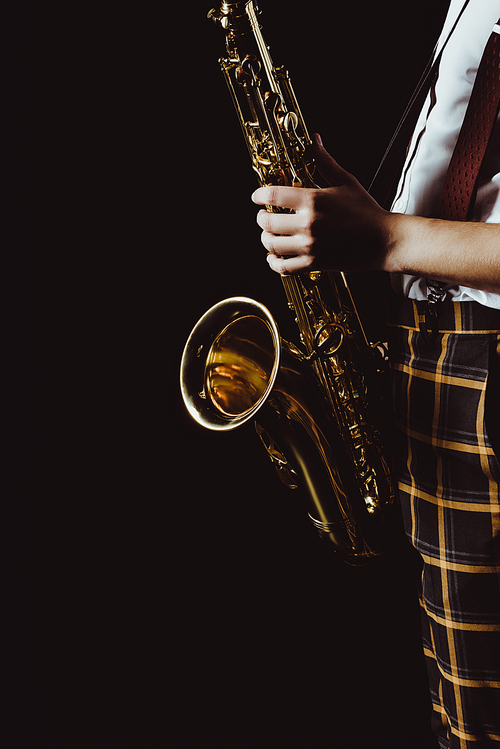cropped shot of stylish young musician holding saxophone isolated on black