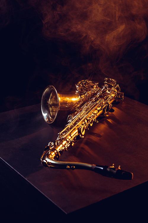 professional shiny saxophone in smoke and backlit on black