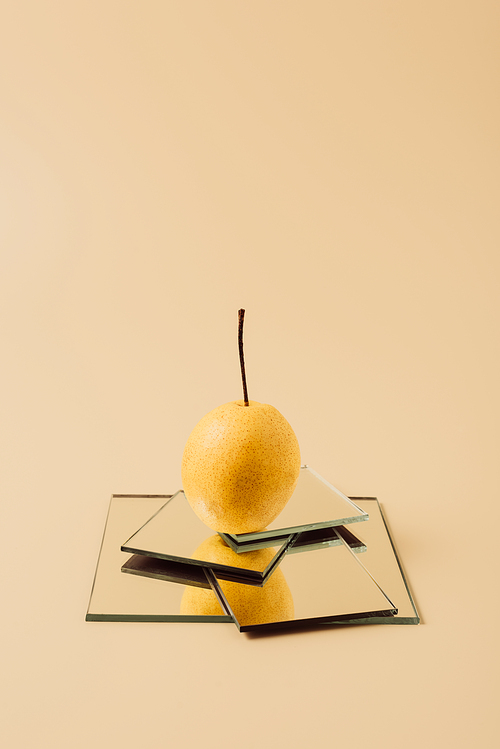 one yellow pear on mirrors on beige table