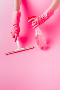 cropped image of female cleaner in rubber gloves cleaning floor by squeegee with cleaning fluid, pink background