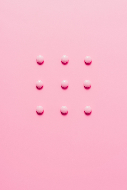 top view of composed pink pills on pink surface