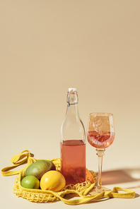 close-up view of drink in glass and bottle, string bag and fresh fruits on brown