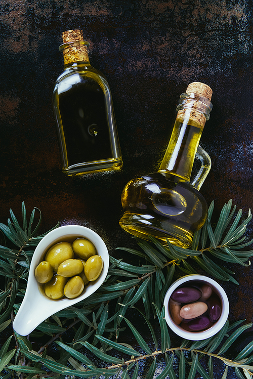 top view of two bottles of homemade olive oil and olives on shabby surface