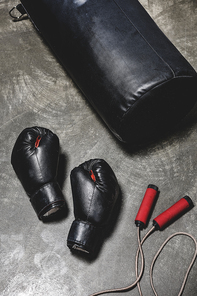 punching bag with jumping rope and boxing gloves on concrete surface