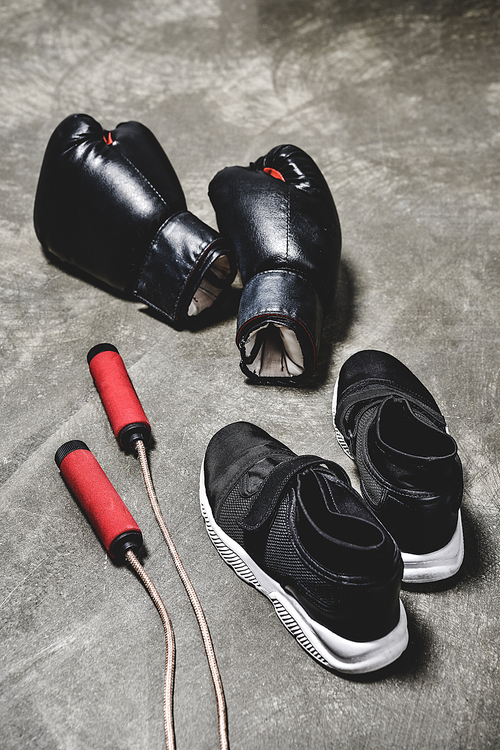 sneakers with jumping rope and boxing gloves on concrete surface