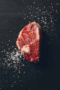 top view of raw meat steak and salt on surface in kitchen