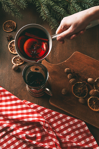 partial view of person pouring hot spiced wine into glass