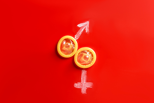 top view of condoms with male and female signs on red background