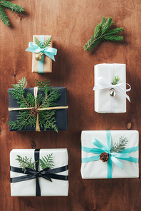 top view of christmas gifts decorated with fir branches and ribbon bows on wooden background