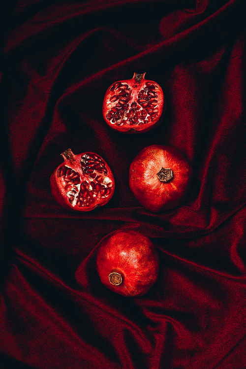 top view of ripe pomegranates on red velvet fabric backdrop