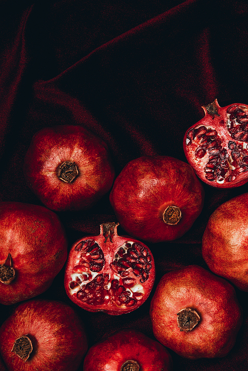 top view of arranged pomegranates on red velvet fabric background