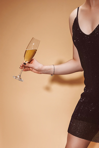 cropped image of woman holding glass of champagne at party on beige