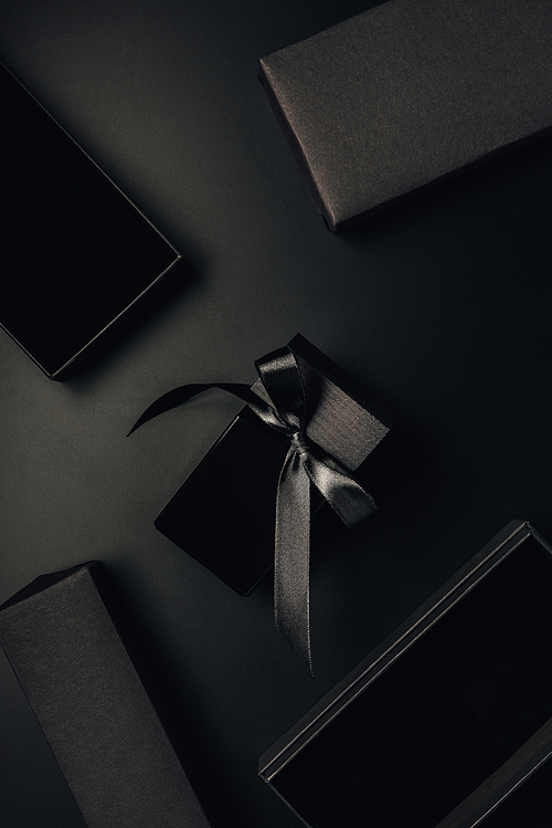 top view of black perfume bottle with bow and boxes on black
