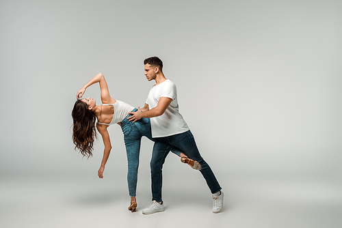 dancers in denim jeans dancing bachata on grey background
