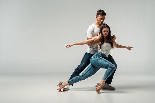 dancers in denim jeans dancing bachata on grey background