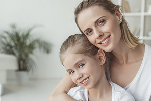 close-up portrait of mother and daughter embracing at home