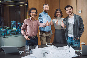 group of successful architects showing thumbs up at office