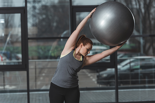 Curvy girl exercising with fitness ball in gym