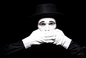 mime covering mouth and looking at camera isolated on black