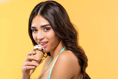 attractive woman eating ice cream cone, isolated on yellow