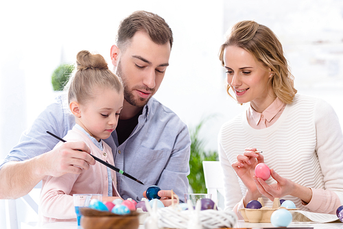 Child and parents coloring eggs for Easter