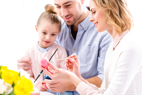 Young woman with family painting Easter eggs