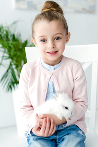 White rabbit sitting on knees of child girl