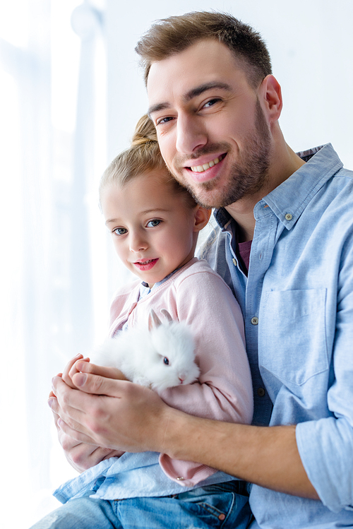 Father and child girl holding white bunny