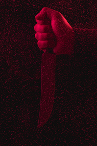 close-up partial view of man holding knife in red light